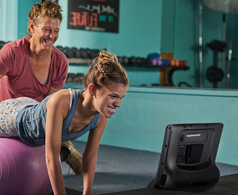 Kvinna som använder sin Tobii Dynavox TD I-Series hjälpmedelsenhet på gymmet