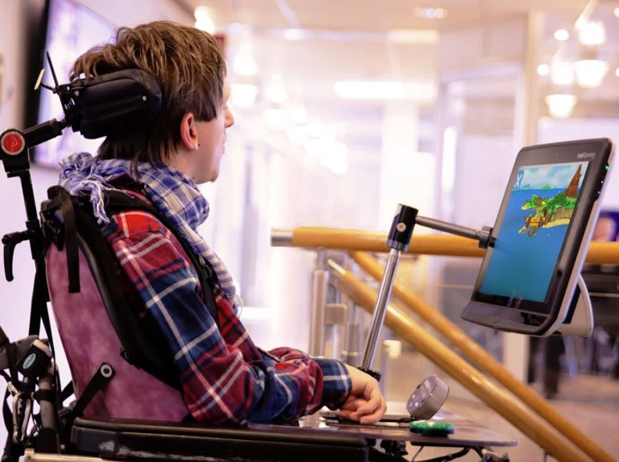 En ung man med cerebral pares använder en ögonstyrd enhet från Tobii Dynavox för att spela spel